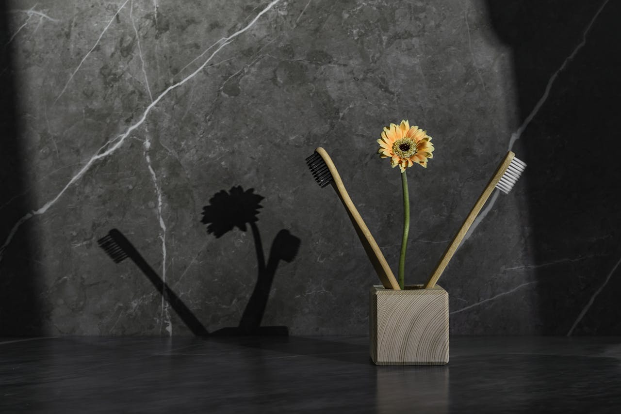 A modern toothbrush holder with a sunflower on a gray surface.